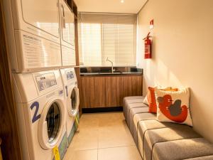 a laundry room with a washing machine and a couch at Easy Life Campus PUC by Xtay - Estúdio completo próximo PUCPR in Curitiba