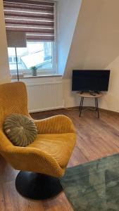 a living room with a chair and a television at Apartament w Centrum - Parking in Ostrów Wielkopolski