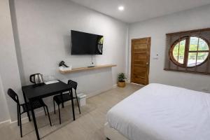 a bedroom with a bed and a desk and a television at The 9 Motel in Ngao