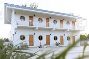 a white house with round windows and a balcony at The 9 Motel in Ngao