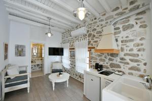 a kitchen with a stone wall with a sink and a table at Psaropoula Guest House in Hydra