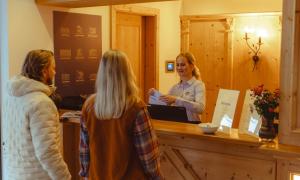 a woman standing at a counter talking to two women at Hotel Abendrot by Alpeffect Hotels in Ischgl