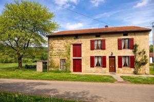 a brick house with red doors and a tree at La madeleine in Malandry
