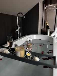 a bath tub with wine glasses and a sink at Amorist Hotel in Dunfermline