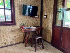 a wooden table with a stool and a television on a wall at Babaland in New Agutaya