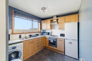 a kitchen with wooden cabinets and a washer and dryer at Harbour Views in Ferryden