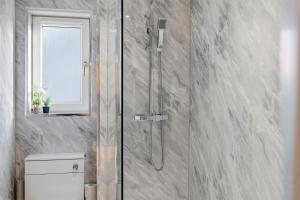 a bathroom with a shower with a toilet and a window at Harbour Views in Ferryden