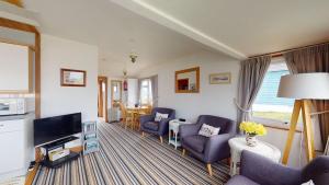 a living room with blue chairs and a television at C29 Regwin, Riviere Towans in Hayle