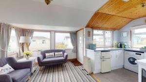 a kitchen and living room with a couch and chairs at C29 Regwin, Riviere Towans in Hayle