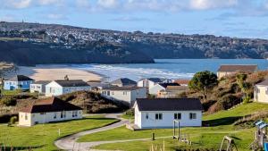 a row of houses on a hill next to the ocean at C29 Regwin, Riviere Towans in Hayle