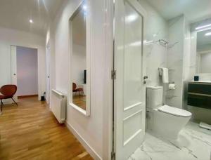 a white bathroom with a toilet and a glass door at Central Urban Elegance in Barcelona +13 photos