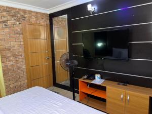 ein Schlafzimmer mit Bett und Flachbildfernseher in der Unterkunft Plot1 Suits in Ibadan