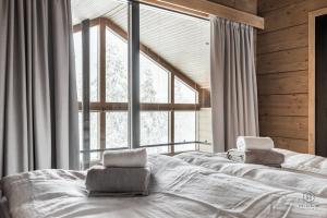 a bedroom with a bed with two chairs in front of a large window at ConstaVilla by Hilla Villas in Kolari