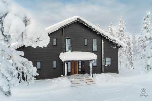 a log cabin in the snow with snow covered trees at ConstaVilla by Hilla Villas in Kolari
