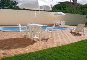 un tavolo e sedie con ombrelloni accanto alla piscina di Apartamento Village Santinho a Florianópolis