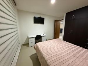 a bedroom with a bed and a desk and a television at Modern and Cozy Home in Acayuca
