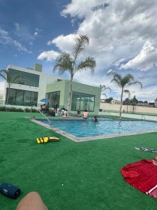 a swimming pool with green grass in front of a building at Modern and Cozy Home in Acayuca