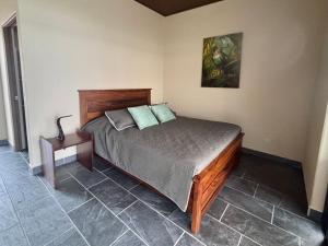 a bedroom with a bed and a table and a painting at Finca Las Raíces Posada Rural in Zarcero