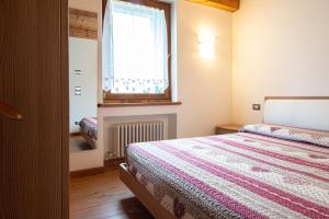 a bedroom with a bed and a window at Accogliente mansarda con vista Dolomiti in Borca di Cadore
