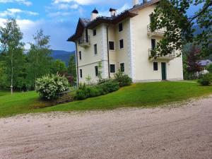 a large white house on a hill with a dirt road at Accogliente mansarda con vista Dolomiti in Borca di Cadore