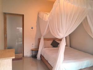 a bedroom with a canopy bed with white curtains at Maha Rama Villas Amed in Amed