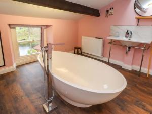 a large white bath tub in a bathroom with pink walls at Kirk Yett in Skipton +40 photos