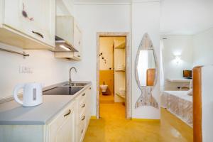 a small kitchen with a sink and a mirror at palazzo beddoro charming apartments in San Pantaleo