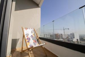a chair on a balcony with a view of a city at Bright Cozy Escape Walk to CFC Self Check-in in Oulad Akkou