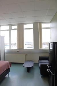 a room with a bed and a chair and windows at Gistiheimilið Ósbær in Blönduós