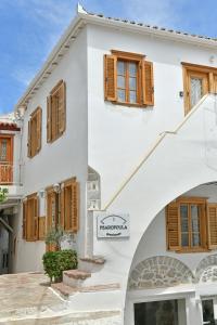 a white house with wooden windows and a sign at Psaropoula Guest House in Hydra