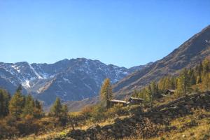 a mountain valley with a cabin on a hill at Almhütte Santnerhof - Hochgebirgshütte 1750m - This is a remote high mountain hut in Virgen