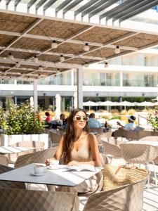 a woman sitting at a table with a book at L'Azure Hotel SPA 4Sup in Lloret de Mar