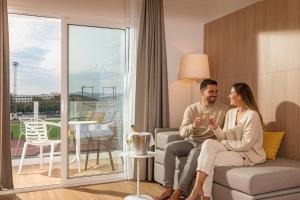 a man and woman sitting on a couch in a living room at L'Azure Hotel SPA 4Sup in Lloret de Mar