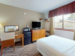 a hotel room with a bed and a desk and a television at Oscoda Lakeside Hotel in Oscoda