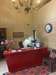 an office with a red desk with a clock on the wall at Willows Boutique Hotel in Pretoria