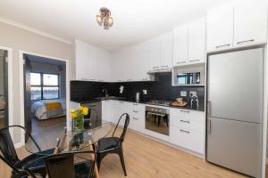 a kitchen with a glass table and a refrigerator at Cape on Porterfield in Cape Town +3 photos