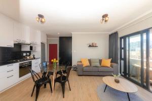 a kitchen and living room with a table and a couch at Cape on Porterfield in Cape Town