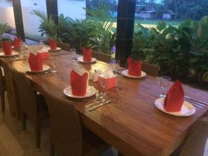 a long wooden table with red napkins and glasses on it at Rosseno Villa in Yogyakarta