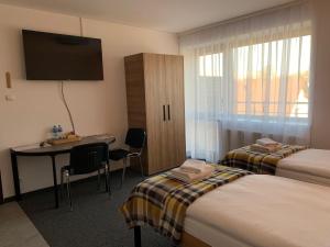 a hotel room with two beds and a desk and a television at Krakstop apartamenty in Krakow