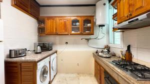 a kitchen with wooden cabinets and a washer and dryer at Appartements Luxe Simo in Fez