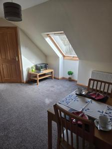 a living room with a table and a skylight at Corrie View in Invergarry