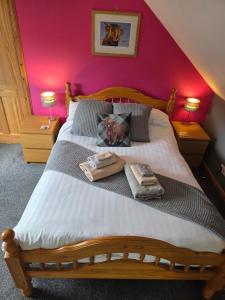 a bedroom with a wooden bed with two towels on it at Corrie View in Invergarry
