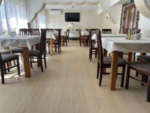 a dining room with tables and chairs and a tv at Pensiunea Hanzu Darius in Gura Râului