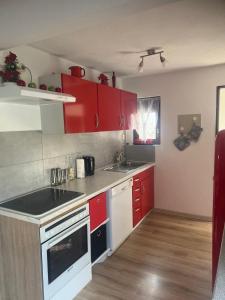 a kitchen with red cabinets and a white stove top oven at Beti Apartment in Nentershausen