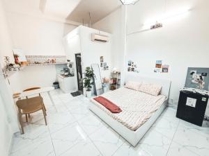 a white room with a bed and a table at December homestay studio 002 in Ho Chi Minh City