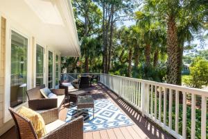 a porch with chairs and tables and palm trees at 13 Angler Hall in Kiawah Island