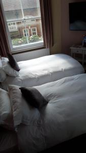 two white beds in a room with a window at Hammersmith Belle in London