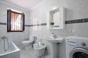 a white bathroom with a sink and a toilet and a sink at Llanes Casa con Terraza y Barbacoa – La Jorcada in Porrúa +35 photos
