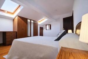 a bedroom with a large white bed and a skylight at Llanes Casa con Terraza y Barbacoa – La Jorcada in Porrúa