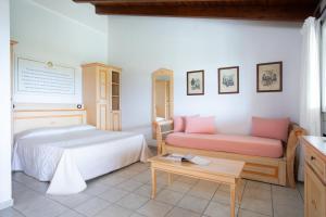 a bedroom with a bed and a couch and a table at Sole d'Estate Agriresidence in Costa Rei
